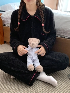 Detail of black plush pajama set featuring contrasting pink trim and button-up design