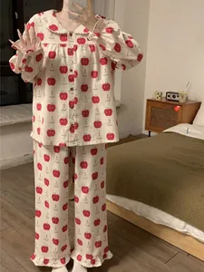 Detail of sweet cotton pajamas featuring red apple prints and ruffled Peter Pan collar