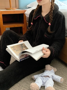 Detail of black fleece pajama set with pink piping trim in cozy bedroom setting