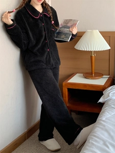 Detail of black coral fleece pajamas with pink piping and buttons in a cozy home setting