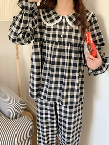 Detail eines schwarz-weiß karierten Pyjama-Sets mit Spitzenkragen und Rüschendetails