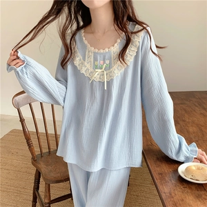 Détail de broderies tulipes et bordures en dentelle sur pyjama bleu clair en coton
