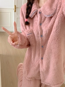 Close-up of pink coral fleece pajamas set with light blue button and pocket trim details