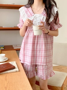 Pink checkered pajama set featuring lace trim and bow details in a cozy home setting
