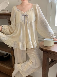 Detail of light yellow crinkle cotton pajamas with ruffles and a purple ribbon bow