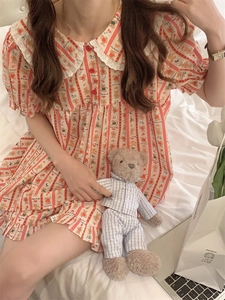 Detail of cartoon bear pajamas with lace collar and red buttons on striped fabric
