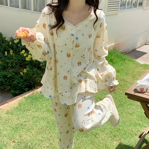 Detail of cream long sleeve bear pajamas featuring lace V-neck and ruffle trim on lawn