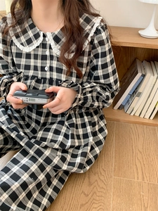 Detail eines schwarz-weiß karierten Pyjamakleides mit Spitzenkragen im Wohnambiente