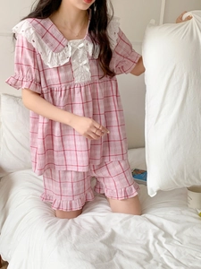 Detail of pink plaid pajamas with white lace collar and delicate bow tie detail