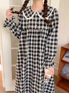 Detail eines karierten Pyjamakleids mit Spitzenkragen und gerüschten Ärmelbündchen
