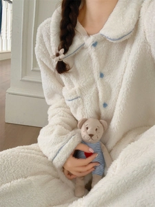 Close-up of cream winter pajamas featuring blue heart buttons and soft fleece texture