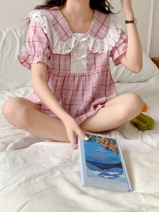 Detail of pink plaid pajamas with lace collar, bow accents and soft cotton texture
