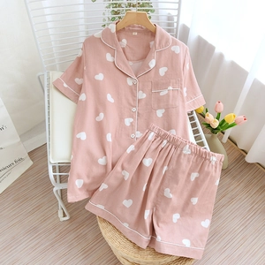 Detail of pink cotton pajama set with white heart patterns on a stylish chair