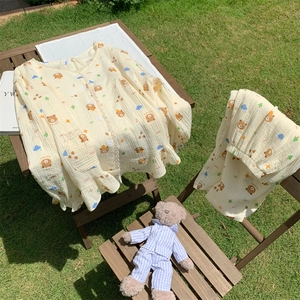 Detail of yellow cotton pajama set with lace edges and cute brown bear prints on a wooden table