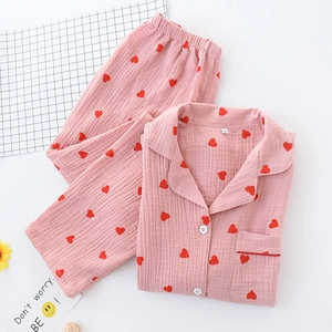 Detailed flat lay of pink cotton pajamas featuring red heart patterns and petal buttons