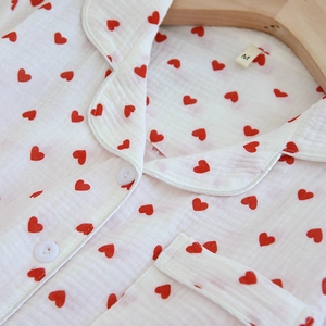Detailaufnahme des weißen Pyjamastoffs aus Baumwolle mit Herzmuster und weißer Paspel