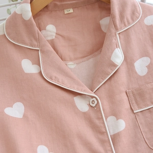 Detail of pink cotton pajama set featuring white heart prints and flower shaped button
