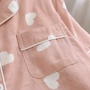 Close-up of pink cotton pajamas featuring white heart patterns and pocket piping detail
