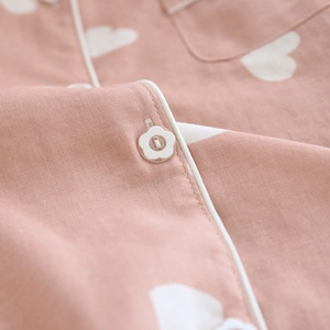 Close-up of pink cotton pajamas showing white heart print and flower-shaped button