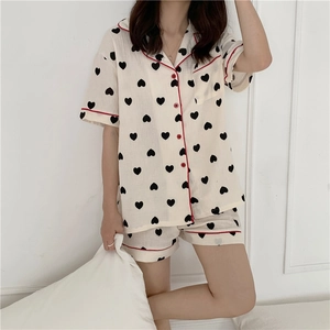 Detail view of cotton gauze pajamas set featuring black hearts and red piping trim