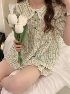 Detailed close-up of cream pajamas with green stripes, lace collar, and bear patterns