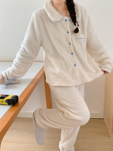 Detail view of white fleece pajamas with blue floral buttons and soft plush texture