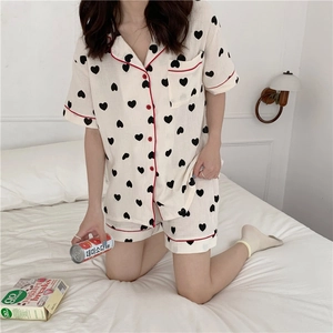 Close-up of cotton pajama set featuring heart patterns and red piping detail on bed