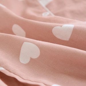 Close-up of soft pink cotton fabric with white heart pattern and premium piping detail
