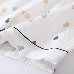 Detail of soft breathable cotton gauze fabric with colorful heart patterns and black piping