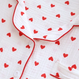 Detail of white cotton pajamas with red heart prints, featuring piping and fabric texture