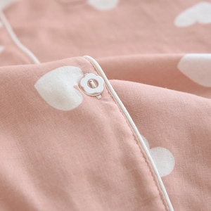 Detail of pink cotton pajamas featuring heart prints and a floral button decoration