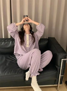 Détail d'un pyjama en molleton lilas avec col en dentelle et poignets à volants sur canapé