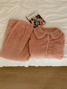 Flat lay of soft pink thermal fleece pajama set with blue piping on a white bed