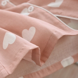 Detailed close-up of pink cotton fabric with white heart pattern and neat piped edging