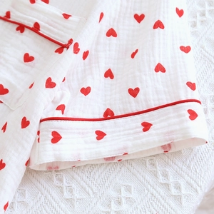 Close-up of double-layer cotton gauze pajama fabric with red heart prints and piping
