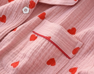 Detail of pink cotton crepe pajama with red heart prints, pocket, and floral button