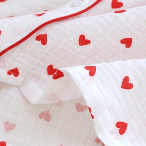 Detailed macro view of white cotton gauze pajama top with red heart pattern print
