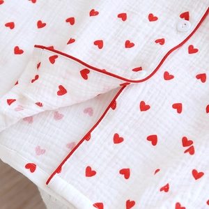 Detail of soft white cotton gauze pajamas featuring red heart patterns and piping