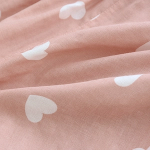 Close-up of soft pink cotton fabric with white heart pattern and breathable texture