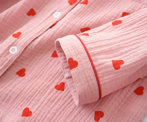 Detail of pink cotton pajamas featuring small heart prints and white floral buttons
