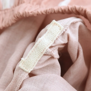 Close-up of elastic waistband and fabric label on light pink cotton gauze pajamas
