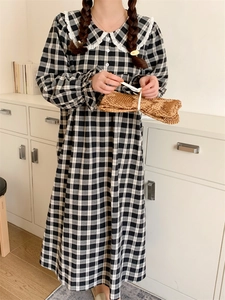 Detail eines schwarz-weiß karierten Pyjamakleides mit Spitzenkragen und Rüschenmanschetten