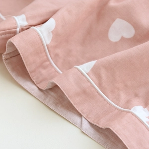 Close-up of pink cotton pajamas fabric with white heart patterns and piping detail