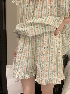Close-up of heart bear print pajamas set with green stripes and ruffled hem