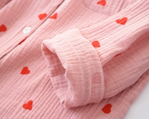 Close-up of pink cotton pajamas featuring red heart prints and soft cuff detailing