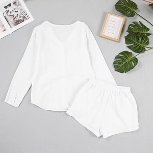 Flat lay of white cotton gauze pajama set with textured V-neck top and elastic shorts