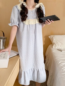 Détail d'une nuisette à carreaux bleu clair avec volants en dentelle et nœud assorti