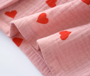 Detail of pink cotton pajama fabric with red heart patterns and soft woven texture