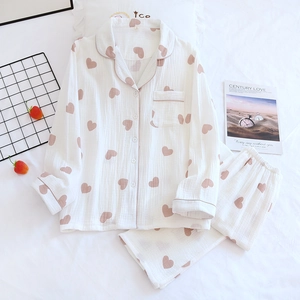 Détail d'un pyjama en coton crêpé à motifs de cœurs roses sur un fond de chambre cosy