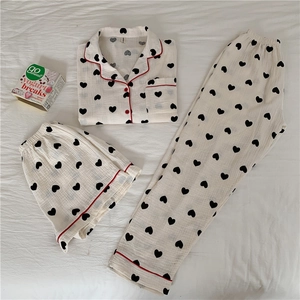 Detail of three-piece cotton gauze pajamas set with heart patterns and red piping trim